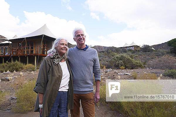 Glückliches älteres Paar vor der Hütte einer Safari-Lodge