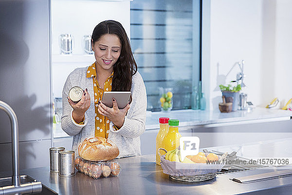 Frau mit digitalem Tablet zur Überprüfung von Lebensmitteletiketten in der Küche