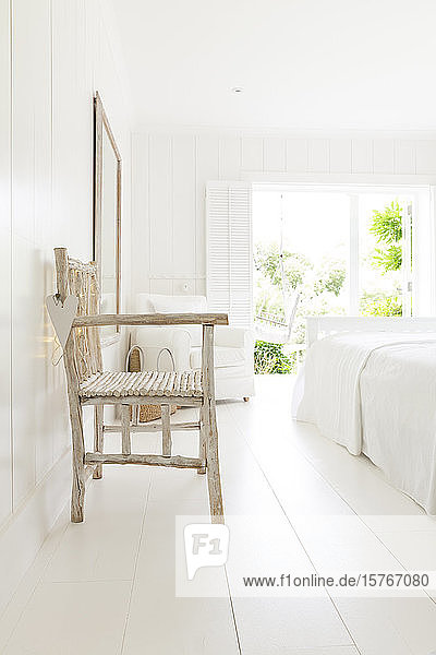 Einfacher Holzsessel im weißen Strandhaus-Schlafzimmer