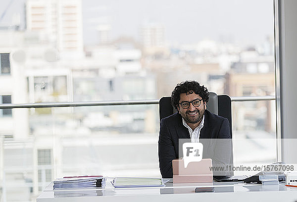 Porträt lächelnder  selbstbewusster Geschäftsmann bei der Arbeit im Büro