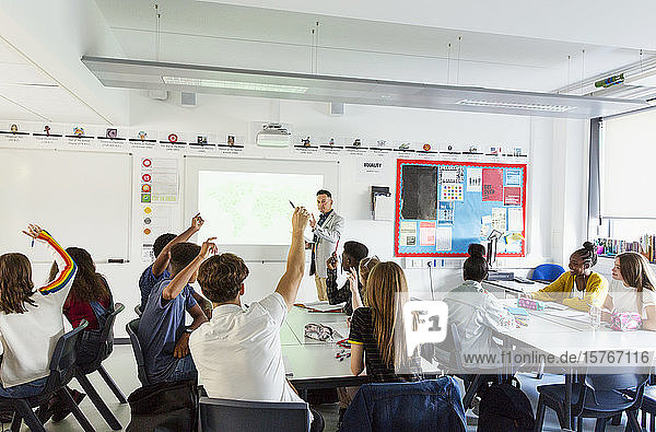 Gymnasiallehrer fordert Schüler mit erhobenen Händen während des Unterrichts im Klassenzimmer auf