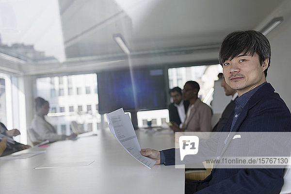 Porträt selbstbewusster Geschäftsmann  der in einem Konferenzraum Papierkram überprüft