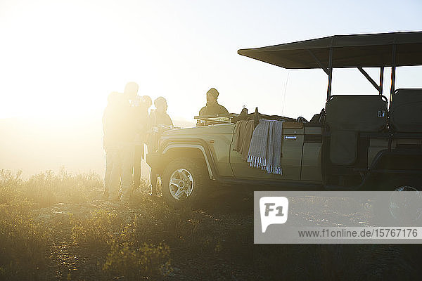 Safaritour-Gruppe trinkt Tee vor dem sonnigen Geländewagen