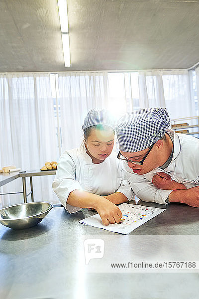 Young students with Down Syndrome looking at recipe in kitchen