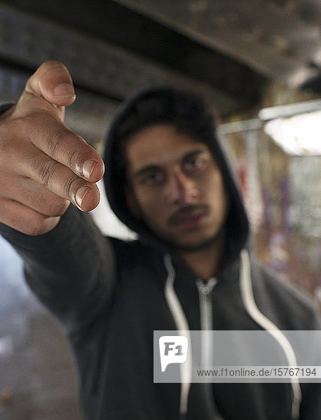 Porträt bedrohlicher junger Mann  der mit dem Finger eine Pistole zeigt