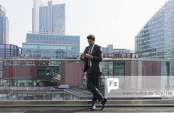 Businessman using smart phone on sunny urban balcony  Shoreditch  London
