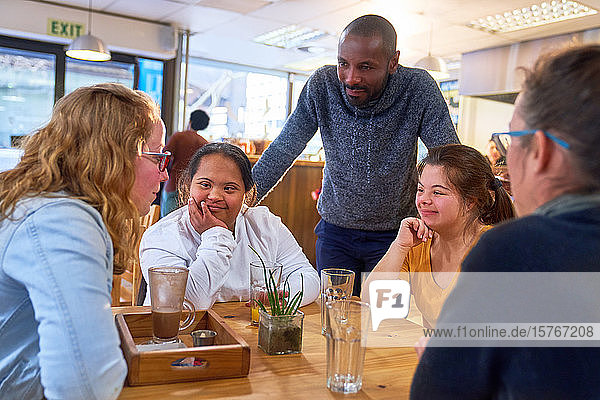 Young women with Down Syndrome talking to friends in cafe
