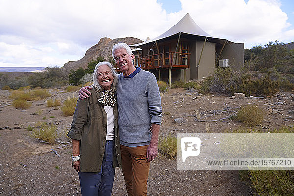 Portrait happy senior couple outside safari cabin