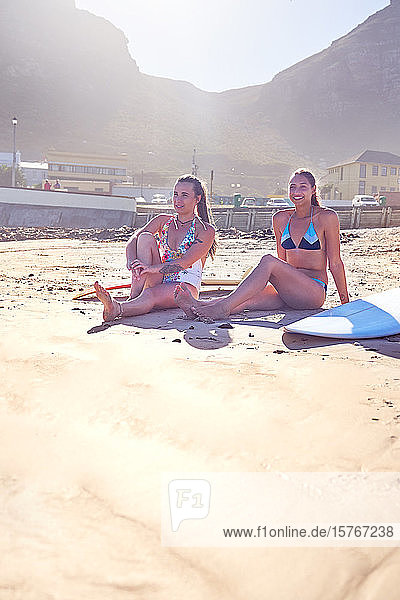 Junge Surfer-Freundinnen entspannen sich am sonnigen Strand
