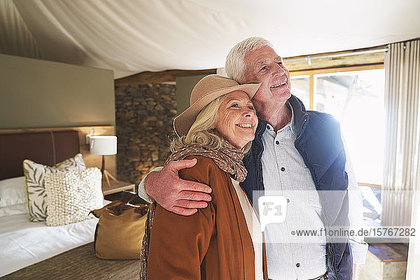 Sorgloses älteres Paar  das sich in einem Safari-Lodge-Hotelzimmer umarmt