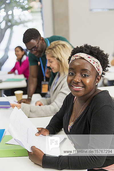 Porträt einer selbstbewussten Studentin mit Papierkram im Klassenzimmer