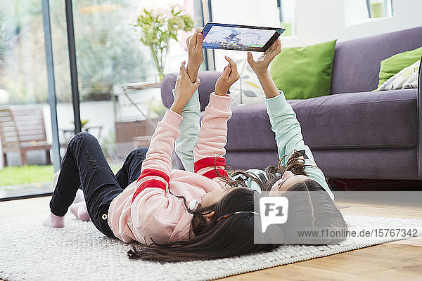 Girls taking selfie with digital tablet on living room floor