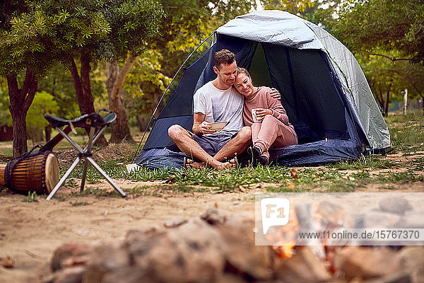 Happy affectionate couple relaxing in tent at campsite