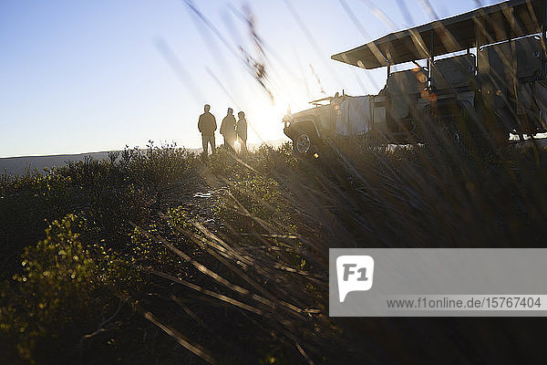 Silhouette Safaritour Gruppe und Geländewagen auf dem Hügel bei Sonnenaufgang