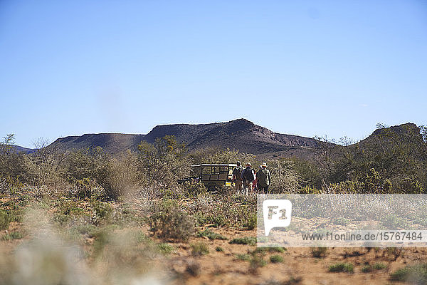 Safari-Tour-Gruppe zu Fuß zum Geländewagen im sonnigen Wildreservat