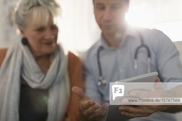 Männlicher Arzt zeigt einem Patienten ein digitales Tablet