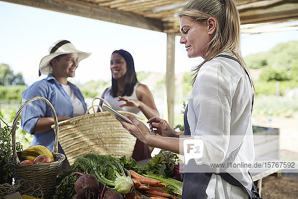 Frau mit digitalem Tablet auf dem Bauernmarkt