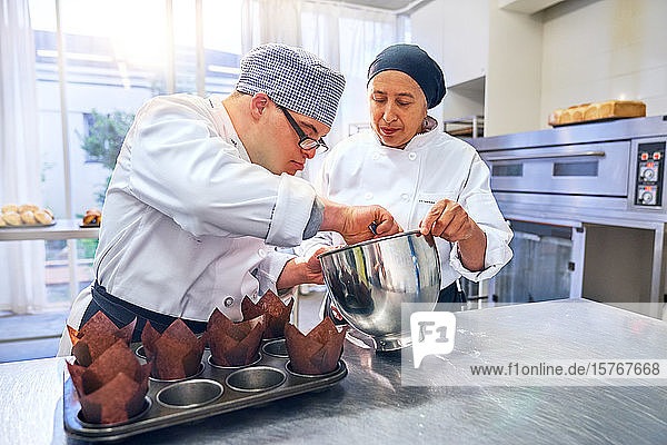 Koch hilft Schülerin mit Down-Syndrom beim Backen von Muffins in der Küche