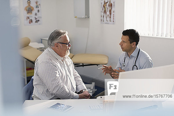 Männlicher Arzt im Gespräch mit einem Patienten in einer Arztpraxis