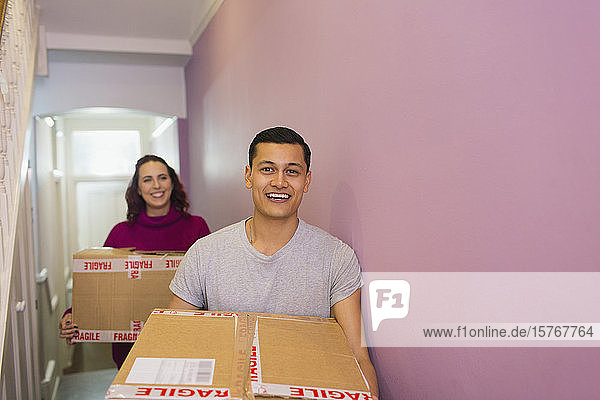 Porträt eines glücklichen Paares  das umzieht und Kartons in den Korridor trägt