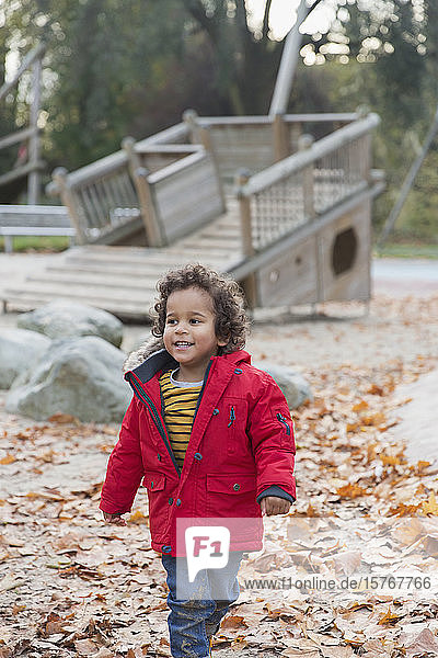 Lächelndes Kleinkind  das im Herbst im Park spazieren geht