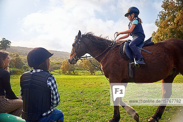 Girl learning horseback riding in rural grass paddock