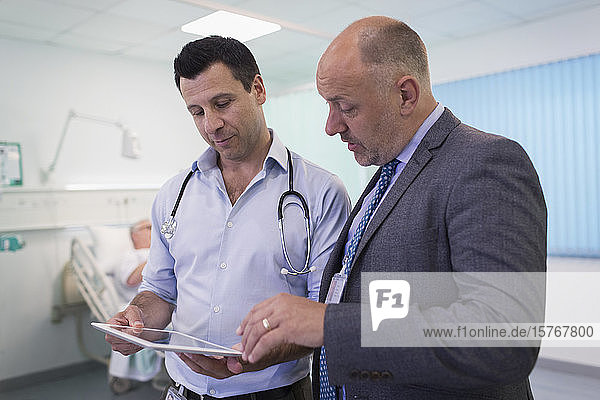 Männliche Ärzte mit digitalem Tablet bei der Visite  Beratung im Krankenhauszimmer
