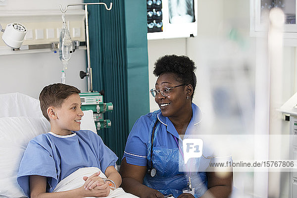 Female nurse talking with boy patient in hospital room