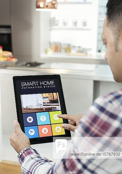 Man controlling smart home navigation system from digital tablet in kitchen