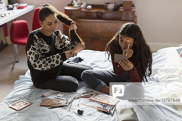Teenager-Mädchen tragen Make-up auf und bürsten sich die Haare im Bett