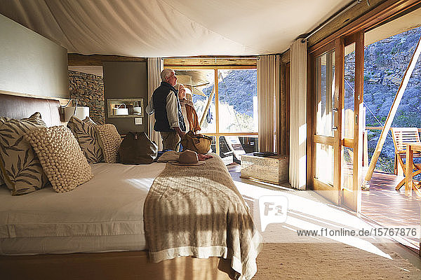 Glückliches älteres Paar bei der Ankunft in einem sonnigen Safari-Lodge-Hotelzimmer