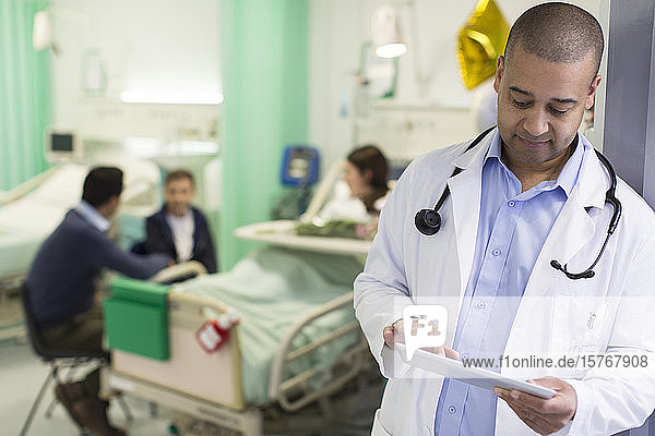 Männlicher Arzt mit digitalem Tablet bei der Visite in einer Krankenstation