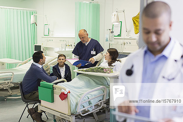 Doctor making rounds  talking with patient and family in hospital ward