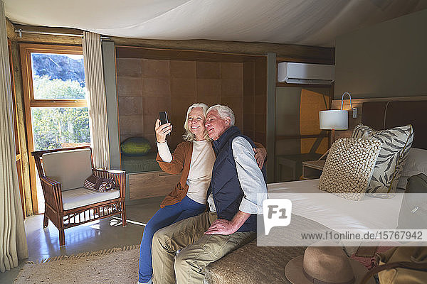 Glückliches älteres Paar macht Selfie mit Fotohandy im Hotelzimmer
