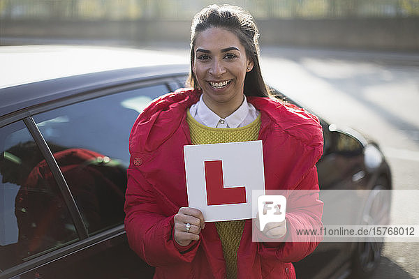 Porträt einer selbstbewussten  glücklichen jungen Frau mit Führerschein im Auto