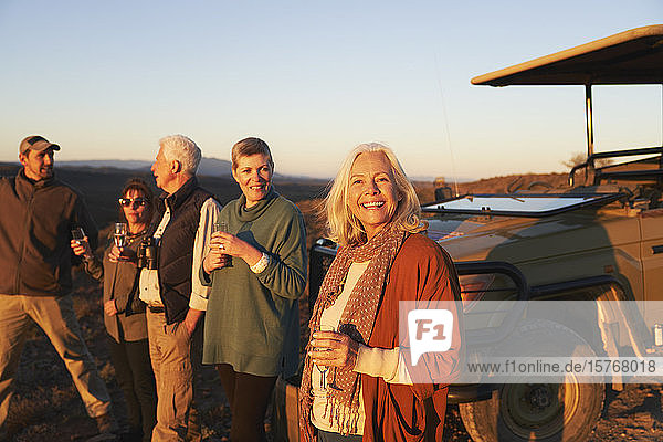 Porträt glückliche ältere Frau auf Safari trinkt Champagner mit Freunden