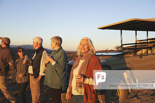 Sorglose ältere Frau auf Safari trinkt Champagner bei Sonnenuntergang