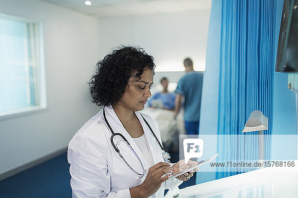Fokussierte Ärztin mit digitalem Tablet im Krankenhauszimmer