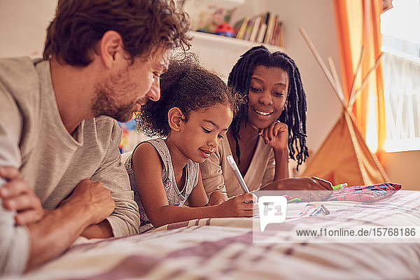 Young family coloring on bed
