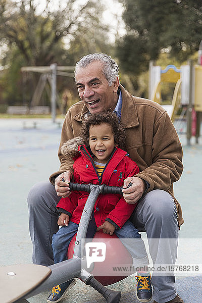 Großvater spielt mit Enkel auf Spielplatzwippe