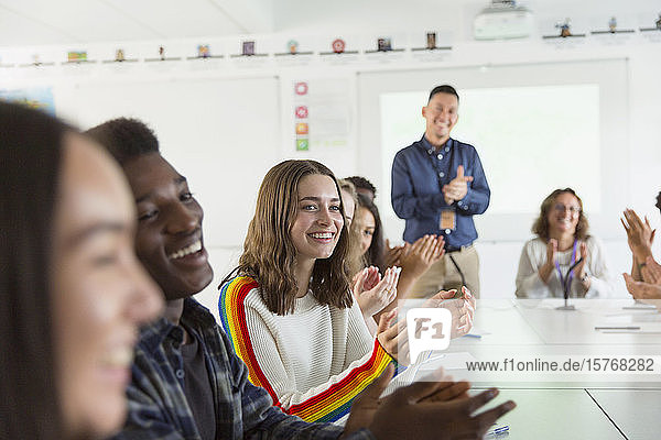 Happy high school students and teacher clapping in debate class