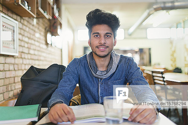 Porträt selbstbewusster junger männlicher Student  der in einem Café lernt