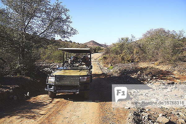 Safari-Gruppe im Geländewagen auf sonniger Schotterpiste