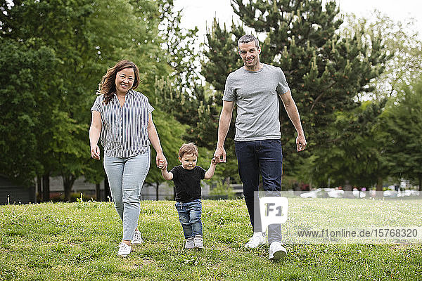 Porträt glückliche junge Familie spazieren im Park Gras