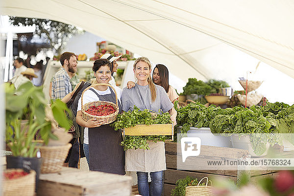 Porträt lächelnde Arbeiterinnen mit Gemüse auf dem Bauernmarkt