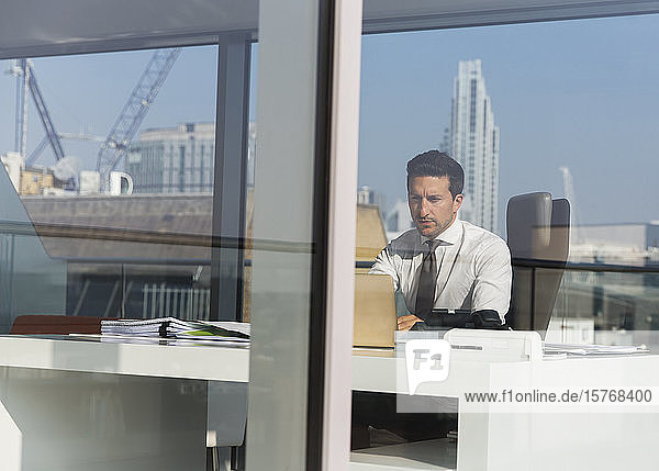 Fokussierter Geschäftsmann  der in einem sonnigen  modernen  städtischen Büro arbeitet