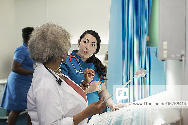 Ärztin und Krankenschwester mit digitalem Tablet im Gespräch im Krankenhauszimmer