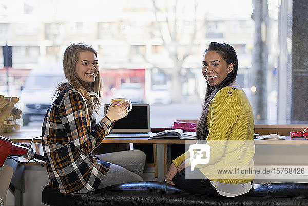 Portrait confident young female college students studying in cafe