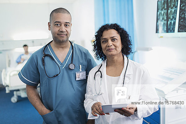 Portrait confident doctor and nurse with digital tablet in hospital room