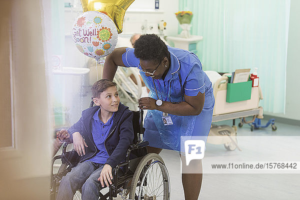 Eine Krankenschwester schiebt einen Jungen im Rollstuhl in einem Krankenhauszimmer
